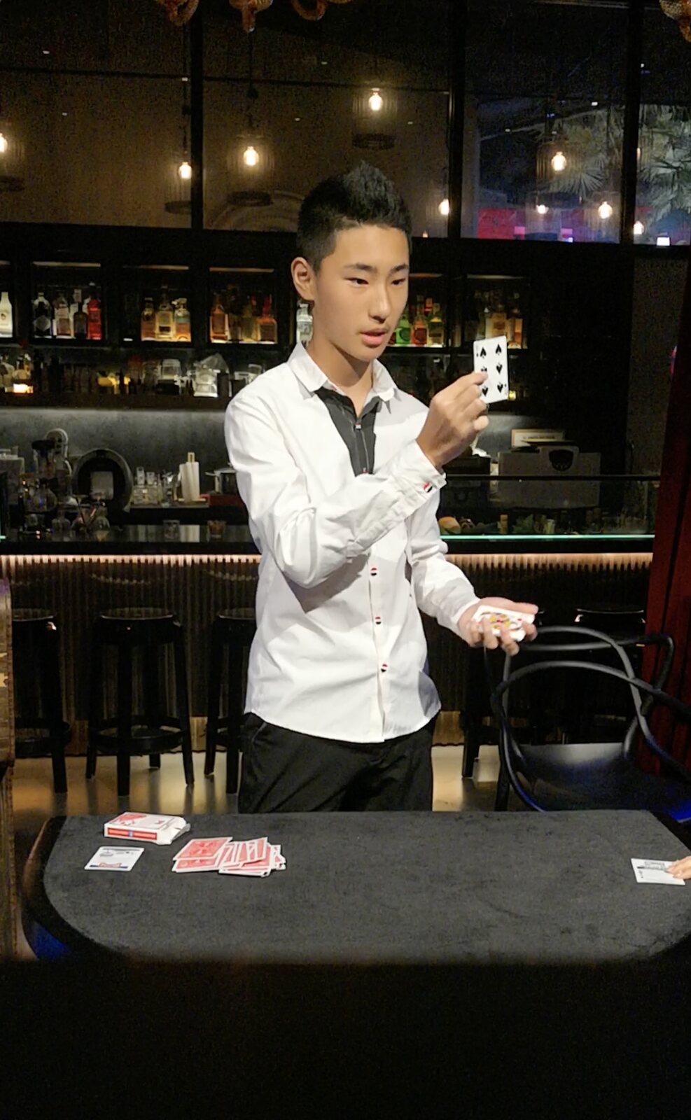 Sihan Fu presenting a playing card during a close-up performance on July 31, 2018